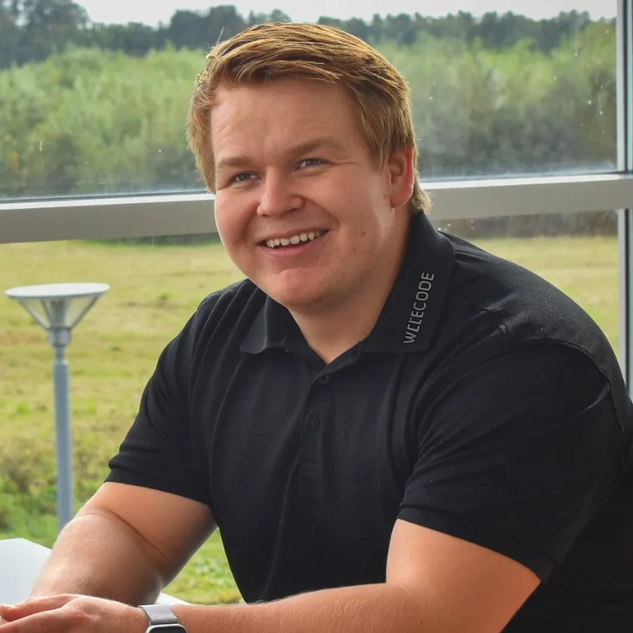 Jacob Hildebrandt Sørensen i en sort Wizecode-polo foran et vindue med udsigt over en mark.